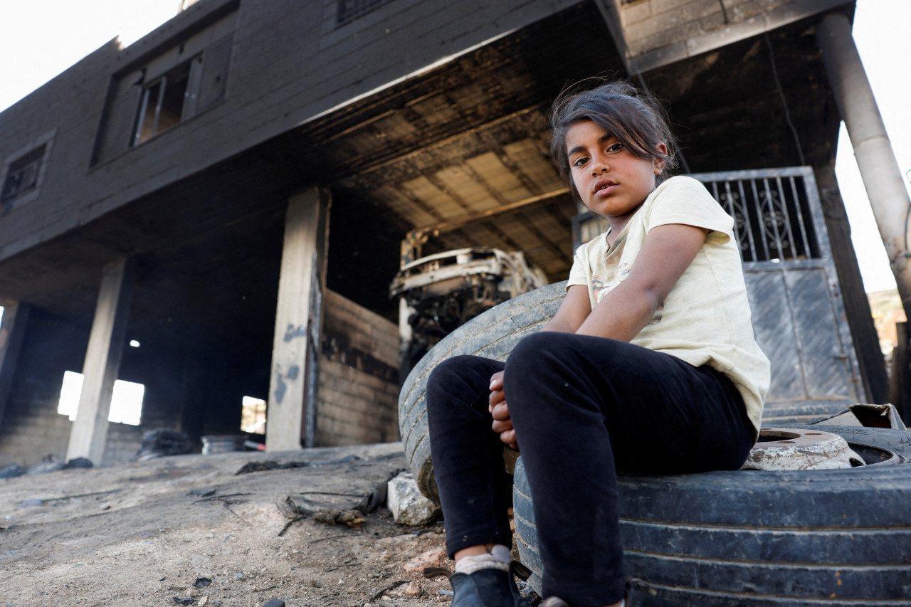 Una niña palestina sentada frente a su casa después del ataque de colonos israelíes. Foto: Reuters